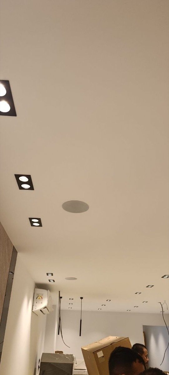 Café ceiling with recessed spotlights, an in-ceiling speaker, and a wall-mounted air conditioning unit