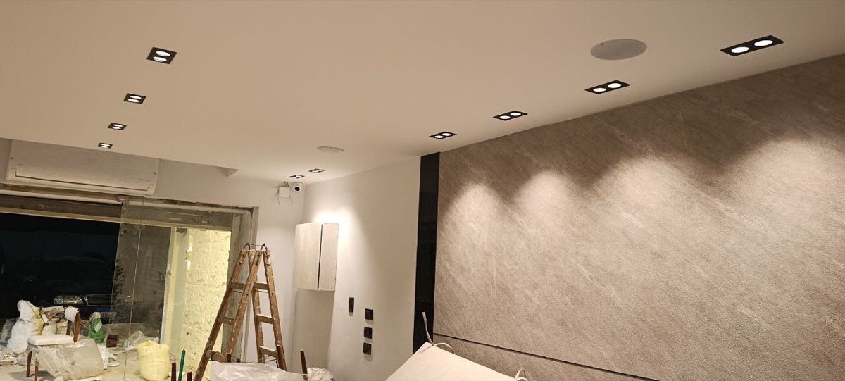 Café ceiling under construction with spotlights and an in-ceiling speaker, beside a textured accent wall