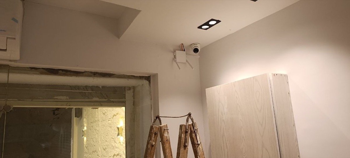 CCTV camera mounted in a corner junction box near a doorway, during construction