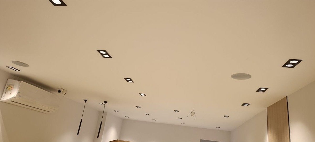 Wide view of the café ceiling with spotlights, in-ceiling speakers, and a CCTV camera