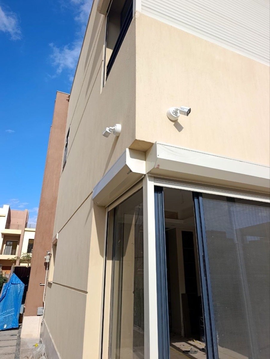 Two CCTV cameras mounted together at a corner of the villa