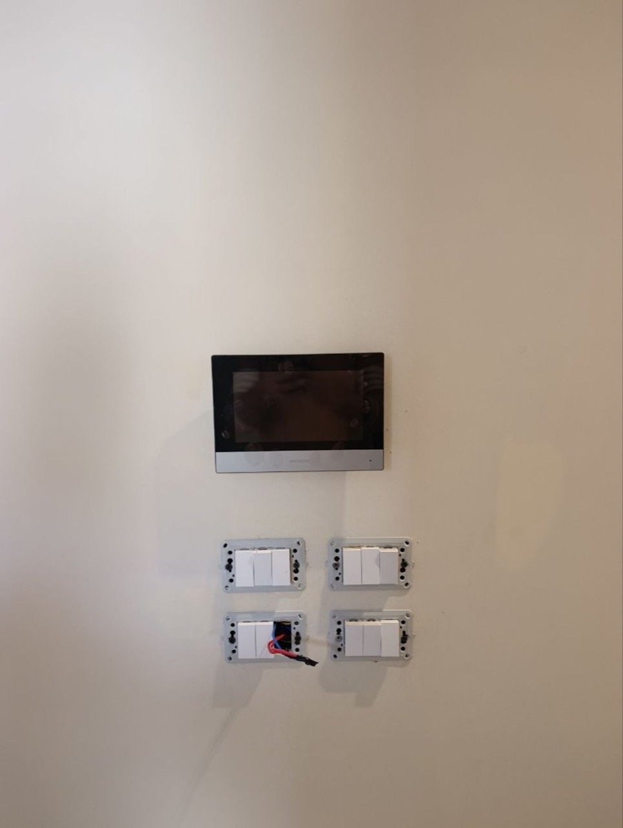 Indoor video intercom monitor mounted above a bank of smart touch switches