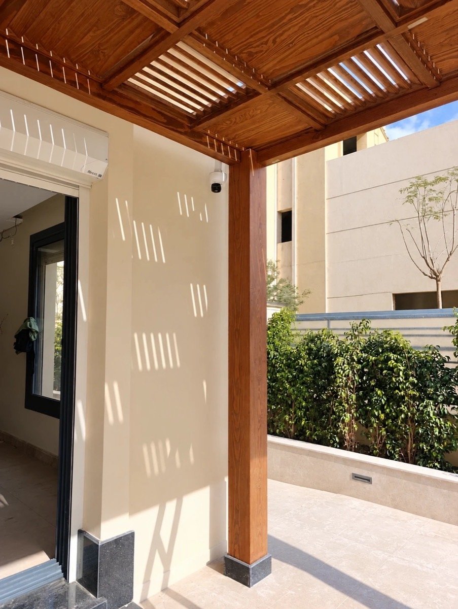 CCTV camera mounted under a wooden pergola, overlooking the finished patio