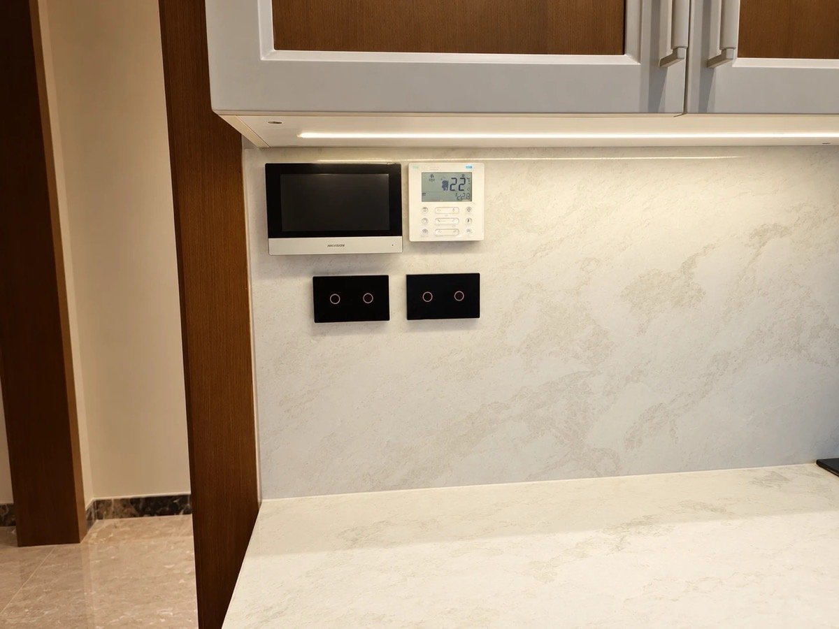 Kitchen wall with a video intercom monitor, a climate controller, and two smart touch switch panels under cabinet lighting