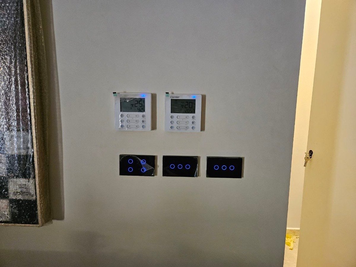 Wall with two climate controllers and three smart touch switch panels near a hallway