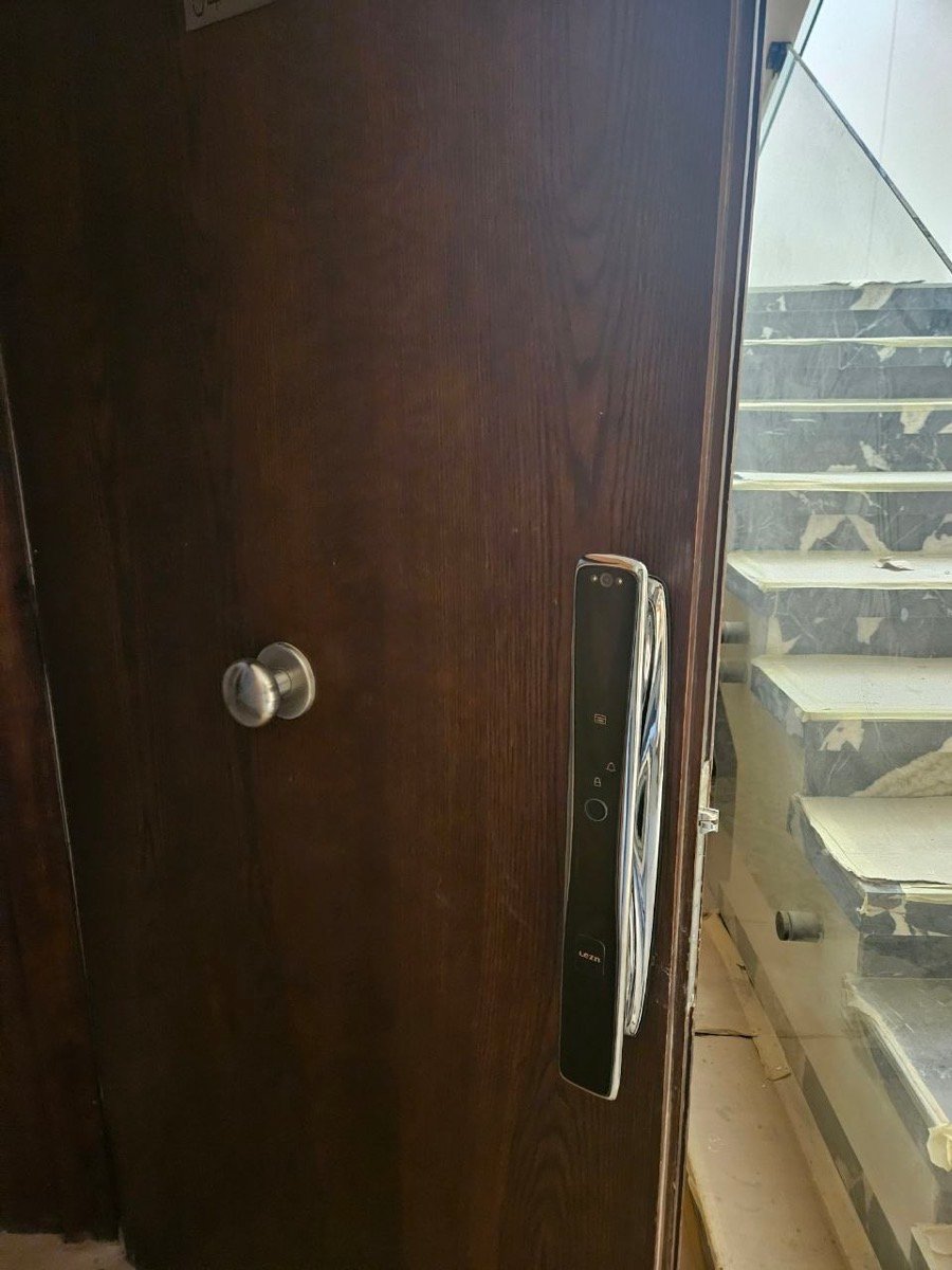 Fingerprint smart door lock installed on a wooden entry door beside a staircase