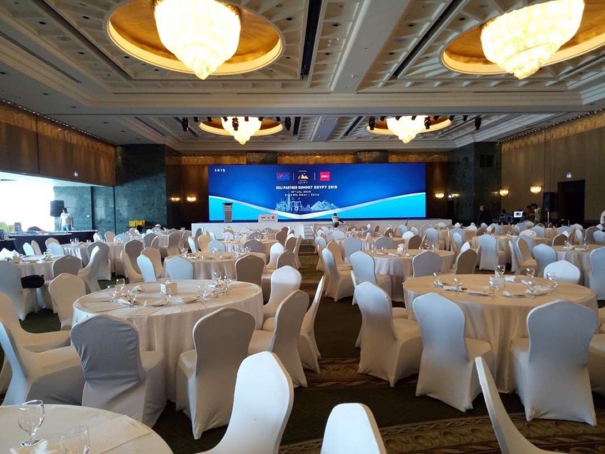 Ballroom set for a corporate summit, with a large LED stage screen displaying the event branding