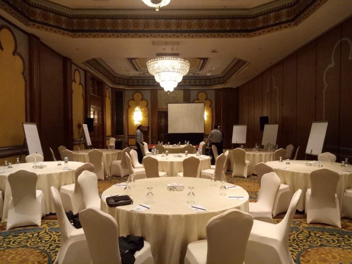 Ballroom arranged for a corporate meeting with round tables, flip charts, and a projector screen